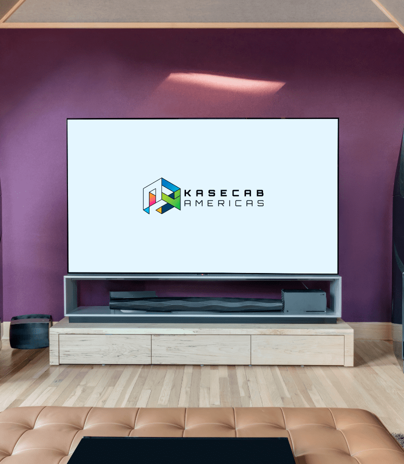 Untitled design (2) A television displaying the Kasecab Americas logo sits on a light wood TV stand against a purple wall in a modern living room.
